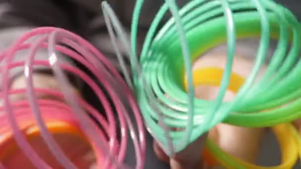 Jolly rainbow slinky with shrinking childish coils in slow motion Macro shot of a plastic rainbow slinky shrinking askew with many colorful coils and forming the mood of joyerfulness, innovation and fest in Xo@-@ mo 