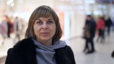 Akıllı kadın siyah bir ceket ve mutlu bir alışveriş merkezinde slo-mo gülümseyen şık kazak şık bir saç kesimi ile neşeli sarışın bir kadın portresi slo-mo içinde büyük camları olan bir alışveriş merkezinde gülümseyen