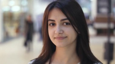 İnsanlar yavaş hareket neşeli bir bluz ayakta ve havadar koridorları ve insanlar yavaş hareket ile modern bir alışveriş merkezinde gülümseyen genç bir şık güzellik görünümünü ile modern bir alışveriş merkezinde gülümseyen güzel esmer kadın