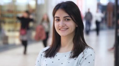 Bob saç kesimi bir zarif siyah ceketli ve sportif kapüşonlu bir alışveriş merkezinde yavaş yavaş hareket gülümseyen bir sarışın kadın neşeli görünümünü havadar windows ile bir alışveriş merkezinde duran kadın düldül