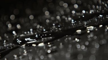 Ağır çekimde harika makro çekim siyah ve gri su mizzling yağmur damlacıkları altında ıslak siyah ve gri yüzeyi parlak ve gülen yavaş yağmur damlaları ile sağlam bir yüzeye su sıçramalarına. 