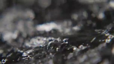 Parlak siyah ve beyaz su slo-mo siyah ve beyaz su yüzeyinde bazı kaba ve vahşi gri yavaş yavaş yavaş akan Fairylike makro çekim biraz engebeli yüzeyini örten. Sanat konusunda hava atan görünüyor.