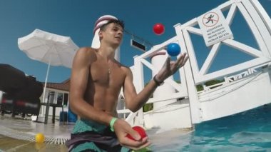 Yavaş hareket etkileyici bir plajda denize Şarm-El-Sheikh Mısır'daki ağır çekimde plastik topları hokkabazlık şort sportif bir genç adam görünümünü Mısır'daki bir deniz plajda plastik topları ile akıllı adam juggles