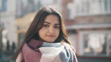 Modaya uygun elbiseleri slo-mo Inspiring görünümünde meraklı bir genç kadının fantezi eşarp ve ceket arıyor aslant ve sokakta gülümseyen Kış kış slo-mo sokakta merak ile seyir tatlı kız        