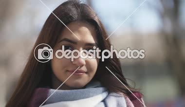 Düşünme ve park slo-mo gülümseyen romantik esmer kız modaya uygun giysiler slo-mo heyecanlı bokeh portre ihale kız kış moda çizgili eşarp ayakta uzun bağsız kıl ile parkta gülümseyen