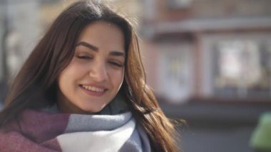Şık Fularlı sevinçle neşeyle kış yavaş çekimde bir sokakta gülümseyen çizgili Fularlı uzun bağsız kıl ile etkileyici görünümü çok hoş bir kız, ağır çekimde kışın bir sokakta gülümseyen şirin kız. 