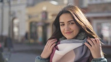 İyimser kız açık havada sokakta kadar romantik bir kızın slo-mo neşeli görünümünde kışın iki el ile sırayla onun eşarp koyarak ve bir sokakta slo-mo kışın gülümseyen uzun bağsız kıl ile smartening bir yün, İpek eşarp