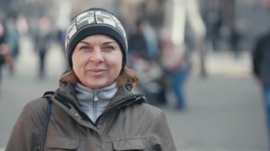 Akıllı kadın örgü şapka ve slo-mo neşeli ince sarışın bir kadın ayakta ve ağır çekimde sonbaharda güneşli parkta gülümseyen örme şapka içinde harika manzarasını arka sokakta gülümseyen bir sportif ceket