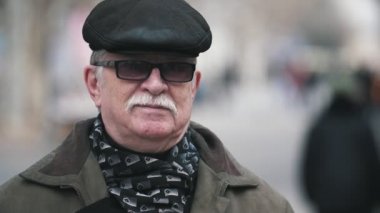 Mutlu komuta sizde düz bir kapak ve düz bir kapak içinde bıyıklı slo-mo iyimser bir gülümseyen beyaz saçlı adam görünümünü bir sokakta gülümseyen güneş gözlüğü ve slo-mo sonbaharda bir sokakta duran karanlık güneş gözlüğü