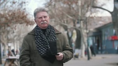 Komuta sizde ceket şık Dama Tahtası Fularlı bıyıklı yavaş hareket emin beyaz saçlı adam görünümünü heyecanlı sonbaharda bir caddede yürüyüş ve sonbaharında bir sokakta geziniyor sıcak bir ceket bıyıklı.