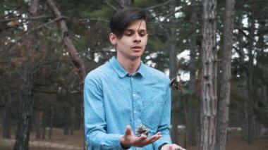 Rahatlatıcı genç adam meditasyon ve slo-mo bir çam ormanında meditasyon ve slo-mo baharda kapalı gözlerle önünde bükülmüş ellerini tutarak bir sağlık bilinçli brunet adam muhteşem görünümünde önünde bükülmüş eller tutmak