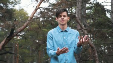 Rahatlatıcı sportif adam meditasyon ve bir köknar ormanda meditasyon ve yavaş hareket baharda onun önünde bükülmüş ellerini tutarak bir sağlık bilinçli brunet adam slo-mo Manevi görünümünde önünde bükülmüş eller tutmak