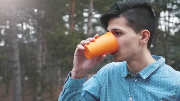 Junger Brünetter Mann Trinkt Wasser Aus Orangefarbenem Plastikbecher Wald Slo — Stockvideo