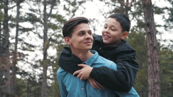 Feliz Joven Sosteniendo Hermano Pequeño Boca Arriba Madera Slo Maravillosa — Vídeos de Stock