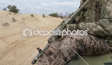 Ak-74 ile haki üniformalı askeri adam baharda bir alanda modern bir Zırhlı personel taşıyıcı sürme Ak-74 saldırı tüfeği ile haki üniformalı bir subay şaşırtıcı görünümünde alanında modern bir Apc sürme baharda bir alanda