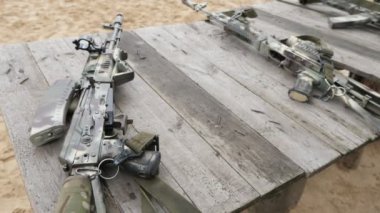 Optik manzaraları ile modern saldırı tüfeği baharda bir dizi ahşap bir masa üzerinde yatan dergi olmadan optik manzaraları ile gelişmiş saldırı tüfekleri heyecan verici görünümü güneşli bir günde askeri bir alanda ahşap bir masa üzerinde yatıyor 