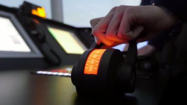 Donanma subayı bir ticaret gemisi nde yarı yuvarlak rota cihazının kolunu çekerek bir donanma subayının harika görünümüne basarak ve insanlarla bir ticaret gemisi kabininde yarı yuvarlak bir rota cihazının kolunu çekerek