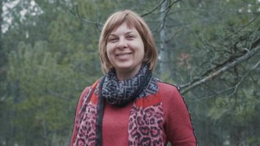 Slo-mo baharda bir çam ağacında gülümseyen süslü bir eşarp ile mutlu sarışın kadın şık bir eşarp ve ceket slo-mo bir çam ahşap ayakta bir bob saç kesimi ile gülümseyen sarışın bir kadının neşeli görünümü