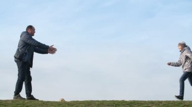 Ilham baba slo-mo bir kenara el ele tutuşan mutlu bir baba ve slo-mo ilkbaharda güneşli bir günde düz bir alanda onun atlama çocuk yakalamak slo-mo amazing görünümünde ilkbaharda güneşli bir günde çim onun atlama oğlu yakalamak