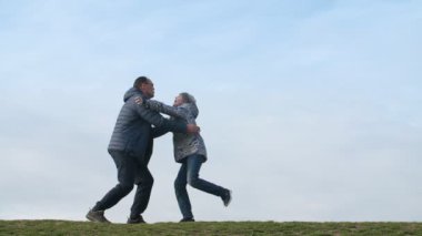 Neşeli baba slo-mo bir kenara el ele tutuşan mutlu bir baba ve slo-mo ilkbaharda güneşli bir günde düz bir alanda onun atlama çocuk yakalamak slo-mo Yürekli görünümünde ilkbaharda güneşli bir günde çim onun atlama oğlu yakalamak