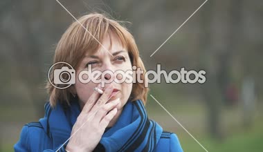 Ayakta ve bir sigara yavaş heyecanlı bokeh portre ayakta, düşünme ve bir parkta bahar yavaş sigara şık bir sarışın kadının bir parkta rahat sarışın kadın