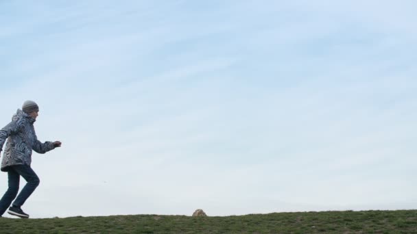 Hilarische Jongen Rennen Springen Een Groen Veld Met Een Blauwe — Stockvideo