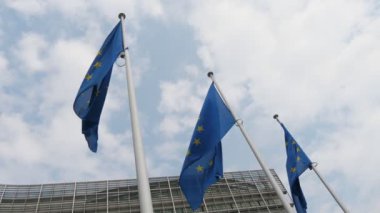 İlkbaharda Brüksel'deki resmi binanın girişinde sallanan üç Ab bayrağı, ilkbaharda güneşli bir günde Brüksel'deki Avrupa Birliği genel merkezinde dalgalanıyor üç Avrupa Birliği bayrağının etkileyici görünümü. Gökyüzü mavi ve beyaz..