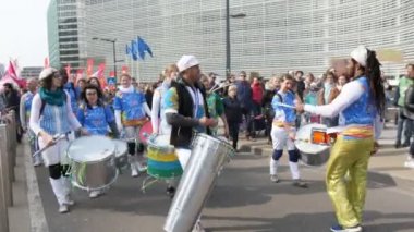Brüksel, Belçika - 30 Mart 2019: İlkbaharda güneşli bir günde bazı yönetim evlerinde bir sokakta büyük ve uzun davullarla yürüyen yeşil barış protestocularının çok renkli görünümü 