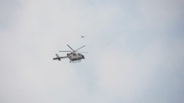 Brüksel, Belçika - 30 Mart 2019: Slo-mo'da ilkbaharda Brüksel caddesinde düzeni korumak için açık mavi gökyüzünde havada dolaşan bir rotorlu polis helikopterinin çarpıcı görüntüsü