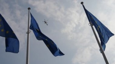 Yavaş çekimde ilkbaharda gökyüzünde uçan bir polis helikopteri ile üç Ab bayrağı Slo-mo baharda yüksek yükselen bir polis helikopteri ile göksel gökyüzünde gururla uçan Avrupa Birliği afiş etkileyici görünümü