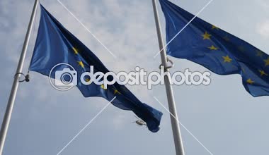 Arka planda bir polis helikopteri ile AB bayrağı. Slo-mo'da sembolik görünüyor Avrupa Birliği bayrağının etkileyici görünümü, Belçika'da uçan bir polis helikopteri ile açık mavi ve bulutlu bir havada dalgalanıyor.
