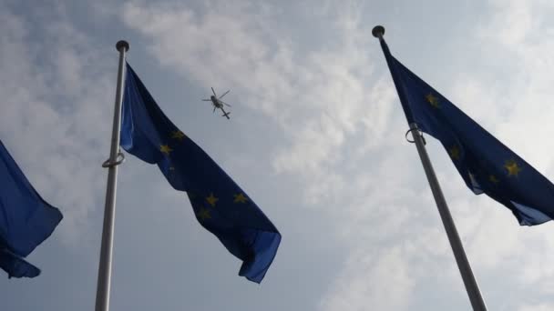 スロモーションで飛行警察のヘリコプターと自由のシンボルのような3つのEuフラグは スローモーションで春の背景に警察のヘリコプターで印象的に揺れる3つの欧州連合の基準の下のビューを下に — ストック動画