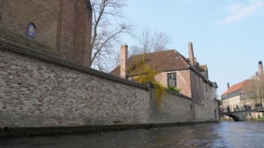 Ortaçağ evleri ve brugge bir taş köprü yakınında yüzen motorbot tarihi binalar ve ilkbaharda güneşli bir günde Brugge insanlarla bir taş köprü ile bir su kanalı bahar Fairytale görünümünde bir taş köprü