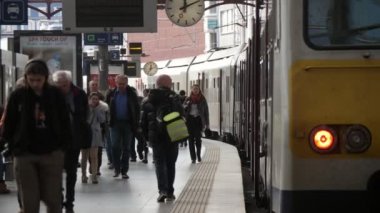Anvers, Belçika - 1 Nisan 2019: Slo-mo'da ilkbaharda Antwerp'te bekleyen modern bir trenle tren istasyonunun platformunda yürüyen birçok insanın heyecan verici görünümü