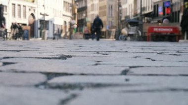 Belçika'da tarihi binaları olan arnavut kaldırımlı bir sokakta yürüyen insanlar slo-mo'da ilkbaharda belçika'da eski tarihi binaları olan arnavut kaldırımlı bir sokakta dolaşan rahat insanların orijinal görünümünde yavaş çekimde