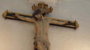 Brüksel, Belçika - 1 Nisan 2019: Brüksel'deki bir katedralde beyaz duvara sabitlenmiş ahşap bir haçın üzerinde duran çarmıha gerilmiş İsa Mesih'in etkileyici görünümü