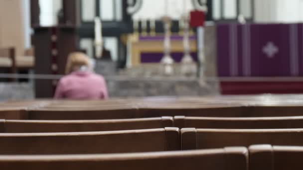 孤独的妇女祈祷在天主教教堂与长椅在比利时宗教视图一个孤独的妇女坐在长凳上 祈祷在天主教克里斯蒂安教堂与耶稣基督的形象在比利时 — 图库视频影像