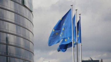 Slo-mo'nun slo-mo'daki evinde mavi arka planlara ve altın yıldızlara sahip üç Avrupa Birliği standardının görünümünde ilkbaharda Avrupa Komisyonu binasında uçan üç Ab bayrağı