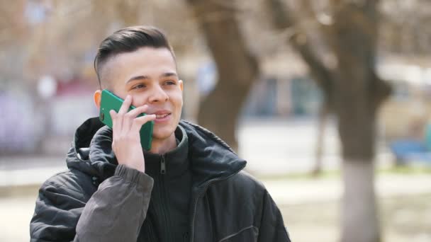 Jesting Brunet Homem Conversando Smartphone Sorrindo Parque Primavera Vista Otimista — Vídeo de Stock