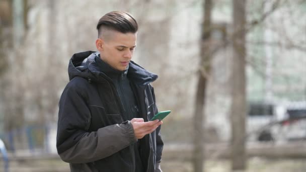 Kendine Güvenen Genç Brunet Adam Baharda Bir Parkta Akıllı Telefon — Stok video