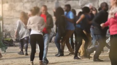 Brüksel, Belçika - 1 Nisan 2019: Yavaş çekimde güneşli bir günde aktif olarak dans eden ve yüksek bir taş duvarda dönen gülümseyen insanların komik görünümü