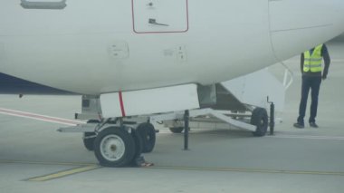 Kiev, Ukrayna - 26 Haziran 2018:İlkbaharda güneşli bir günde büyük bir yolcu turbojeti ayakta, yürürken ve kontrol eden sarı üniformalı havaalanı çalışanlarının orijinal görünümü