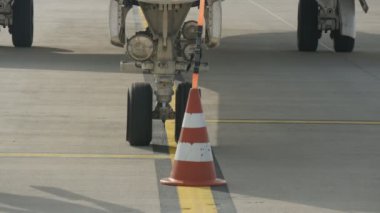 Kiev, Ukrayna - 26 Haziran 2018:İlkbaharda büyük bir yolcu uçağına iniş takımları altına uzun üçgen şekilli bloklar kuran bir aerodrome işçisinin çarpıcı görünümü