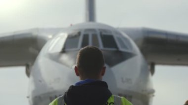 Kiev, Ukrayna - 26 Haziran 2018: İlkbaharda aerodrome turuncu çubuklar kullanarak büyük bir jetin hareketini düzenleyen sarı üniformalı bir trafik kontrolörü etkileyici görünümü