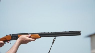 Adam üzerinde ve av tüfeği altında yavaş çekim skeet çekim pratik bir sporcu nun bir çift namlulu av tüfeği tutan ve yavaş çekim güneşli bir günde kil güvercinler hedefleyen etkileyici görünümü