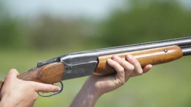 Yavaş çekimde kil hedefleri hedef alan ve tüfek altından ateş eden sportif adam, bir av adamının çift namlulu av tüfeği tetiğini çekmesi ve güneşli bir günde yavaş çekimde kil güvercinleri hedef aldığı nadikkat
