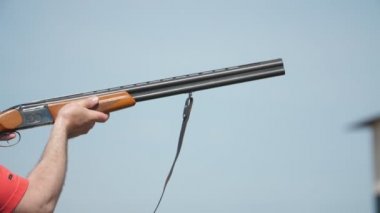 Yavaş çekimde kil hedefleri hedef alan ve tüfek altından ateş eden sportif adam Çift namlulu av tüfeği tetiği çeken ve yavaş çekimde güneşli bir günde kil güvercinleri hedefleyen bir atletin çarpıcı profili
