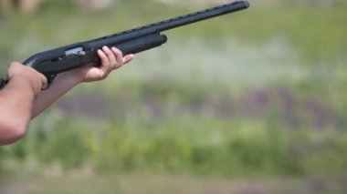 Kil hedeflere ateş eden adam ve slo-mo'daki ihlal kilidinden uçan adam, yan yana tüfeğini tutan sportif bir adamın çarpıcı görüntüsüve skeet plakalarına ateş ederek yazın slo-mo'da uçuşan durumda.