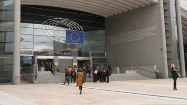Brüksel, Belçika-1 Nisan 2019: AB bayrağı ile Avrupa Parlamentosu girişinde meşgul yetkililerin neşeli görünümü bahar aylarında güneşli bir gün Brüksel 'de giren ve ayrılıyor.