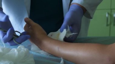 Beyaz üniformalı uzman, tıp odasında ki bir kişinin elini kontrol ediyor Beyaz üniformalı ve beyaz eldivenler giymiş ortopedik cerrahi uzmanının etkileyici görünümü yalan söyleyen bir hastanın elini inceliyor.